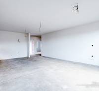 Spacious room in a family house with bare floor and unfinished walls.