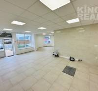 Interior of commercial spaces with large windows and light-colored tiles.