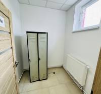 Changing room in commercial premises with storage lockers, white walls, and a radiator.
