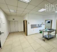 Commercial space with a sink and storage area with white walls and tiles.