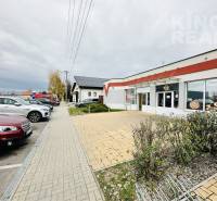 Parking lot and commercial spaces on Štefánikova 267 in Palárikovo with cars and greenery.