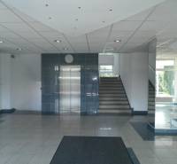 Offices with an elevator and staircase, mirrors reflecting light, tiled floor.