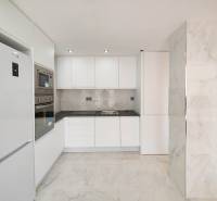A kitchen in a 3-room apartment with white cabinets and built-in appliances, a floor with a marble appearance.