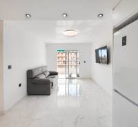 Living room of a 3-room apartment with a marble floor, sofa, and a TV on the wall.