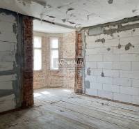 Interior of a family house with exposed brick walls and a wood-patterned floor.