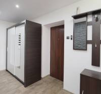 A hallway in a 2-room apartment with a mirrored wardrobe and a wooden decor floor.