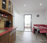 A kitchen in a 2-room apartment with dining, wooden cabinets, and a floor with a wooden decor.