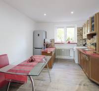 A kitchen in a 2-room apartment with a wooden decor floor and red seating.