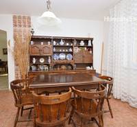 Dining area with wooden furniture and a patterned carpet in a family house.