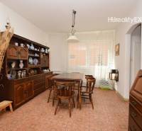 A dining room in a family house with floral wallpaper, wooden furniture, and ceramic accessories.