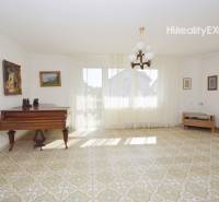 Living room with a piano, patterned floor, and paintings in a family house.