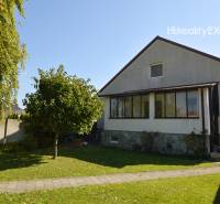 A family house in Hegyeshalom with a grassy garden, a walkway, and trees.