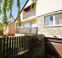 The exterior of a family house in Hegyeshalom with a stone facade and a wooden fence.