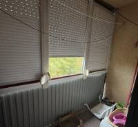 Glazed balcony in a 2-room apartment, with blinds and metal railing.