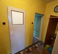 Hallway in a 2-room apartment with yellow walls, white doors, and a colorful carpet.