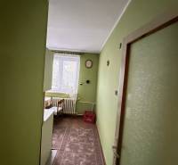 A hallway with green walls, a floor with wooden decor, furniture in a 2-room apartment.