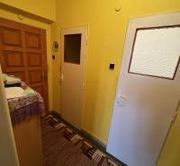Entrance hallway in a 2-room apartment with carpet and yellow walls.