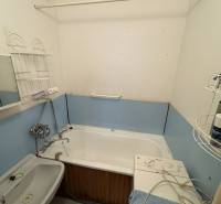 A small bathroom in a two-room apartment with a bathtub, sink, and washing machine.