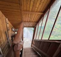 A staircase with wooden paneling in a cottage, overlooking the garden.