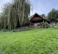 A cottage in Dolné Rykynčice with a spacious lawn and a majestic tree.