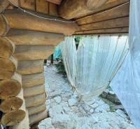 Wooden cottage in Dolné Rykynčice with a stone-paved area and curtains.