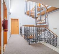 The interior of the building with wood-patterned flooring, white walls, and ceiling lights.