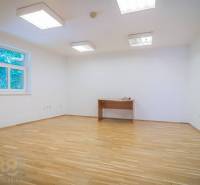 A hallway with a kitchenette in a building with light walls and wooden cabinets.