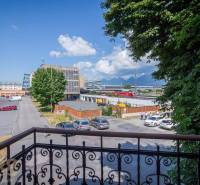 A spacious room in a building with a wood-patterned floor and windows.