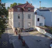Buildings on Halatova Street in Poprad surrounded by greenery, with mountains in the background.