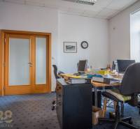 Office in a building with carpet, with various cabinets and a desk under the window.