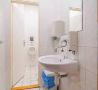 A bathroom in a building with a sink, mirror, and urinal, visible tiles.