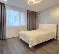A bedroom in a 3-room apartment with a bed, gray curtains, and a floor with a wooden decor.