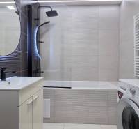 Bathroom with a bathtub, sink, washing machine, and mirror in a 3-room apartment.