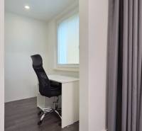 Home office with an office chair and desk in a 3-room apartment with wood-patterned flooring.