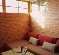 Red brick walls with a sofa and cushions in the Garden area.