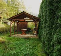 Gardens in Budatín, Žilina: A wooden shelter surrounded by lush green vegetation.