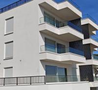 A villa in Trogir with glass balconies and a white facade against the blue sky background.