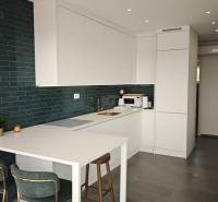A kitchen in a villa with white cabinets and dark tiles, tiled flooring.