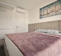 A bedroom in a villa with a bed, wardrobe, and art of sailboats on the wall.