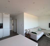 Living room in a villa with a sofa, television, and a bright kitchen.