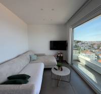 Living room in a villa with a sofa, television, and a view of the city of Trogir.