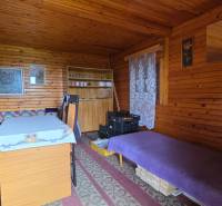 Interior of a garden with wooden paneling, a sofa, and a table with a cover.