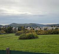 Gardens on A. Hlinka Street in Zvolen, with buildings and forests in the background.