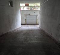 Underground garage with white walls and a rolling gate on Medená Street.