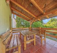 A terrace of a family house with wooden seating and a view of the garden.