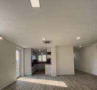 Spacious living room in a family house with a kitchen and a wooden decor floor.