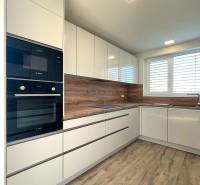 A kitchen in a family house with white cabinets and a wood-patterned floor.