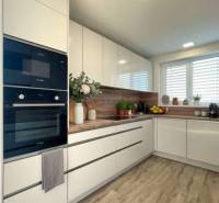 A kitchen in a family house with white cabinets and a wood-patterned floor.