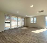 A spacious room with a wooden decor floor and large windows in a family house.