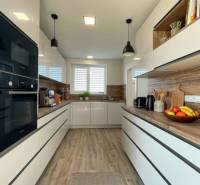 Modern kitchen in a family house with white cabinets and a wood-patterned floor.